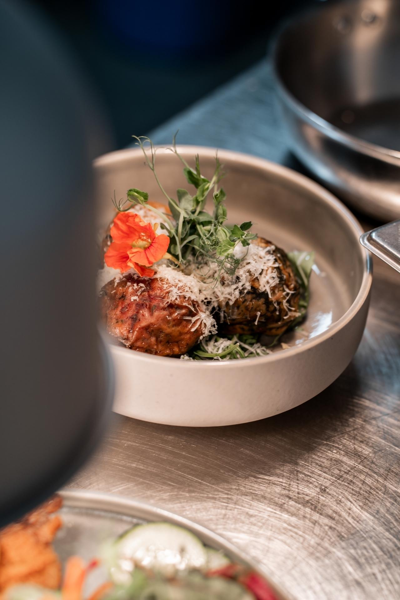 Gericht in einer Schale, garniert mit Kräutern und Blüten.